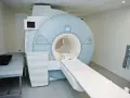 Nowoczesny aparat rezonansu magnetycznego (MRI) w gabinecie lekarskim z kozetką.