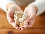 Dłonie trzymają kilka główek czosnku. Choć zdrowy, warto pamiętać o potencjalnych czosnek skutki uboczne.