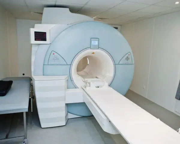 Nowoczesny aparat rezonansu magnetycznego (MRI) w gabinecie lekarskim z kozetką.