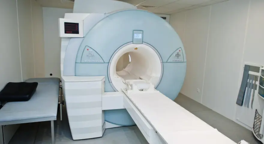 Nowoczesny aparat rezonansu magnetycznego (MRI) w gabinecie lekarskim z kozetką.
