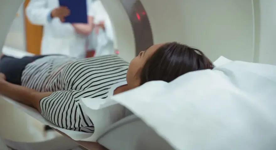 Pacjentka na stole rezonansu magnetycznego. Lekarz z dokumentacją ocenia bezwzględne przeciwwskazania do podania kontrastu.