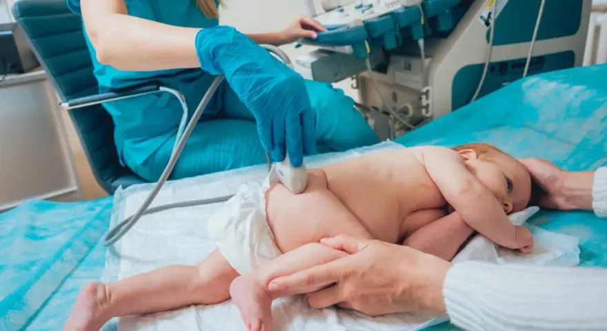 Lekarz wykonuje usg bioderek u niemowlaka. Badanie jest bezbolesne i szybkie, ważne dla rozwoju dziecka.