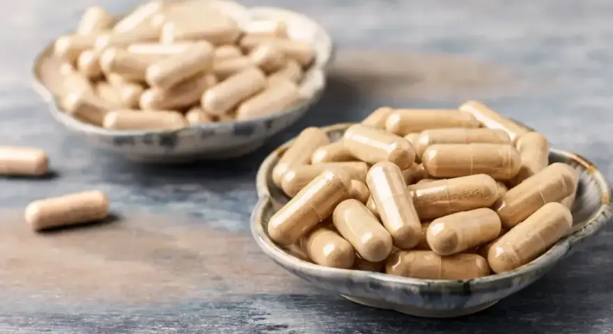 Kapsułki z ashwagandhą w miseczkach. Choć suplementacja bywa pomocna, warto znać potencjalne ashwagandha skutki uboczne.
