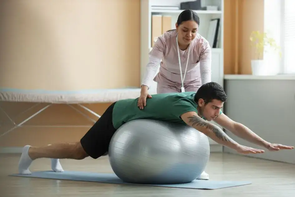 fizjoterapeuta pomaga pacjentowi ćwiczyć